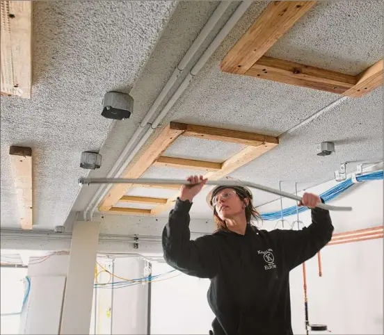  ?? Paul Buckowski / Times Union ?? Kasselman Electric apprentice electricia­n Leah Layton works with conduit at a renovation job at Arbor Hill Elementary School in Albany.