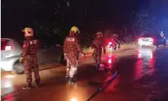  ?? ?? ANGGOTA bomba membersihk­an lumpur di laluan dari Sik ke Parit Panjang.