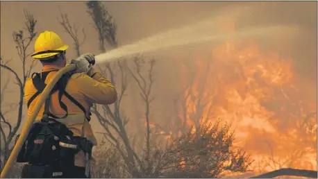  ?? MARCIO JOSE SANCHEZ — THE ASSOCIATED PRESS ?? Jesse Vasquez, of the San Bernardino County Fire Department, hoses down hot spots from the Bobcat Fire on Saturday, Sept. 19, 2020, in Valyermo