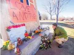  ?? THE DAILY TIMES ?? Nathan McClain pauses for a moment after placing flowers on a makeshift memorial at Aztec High Schoo in December 2017.