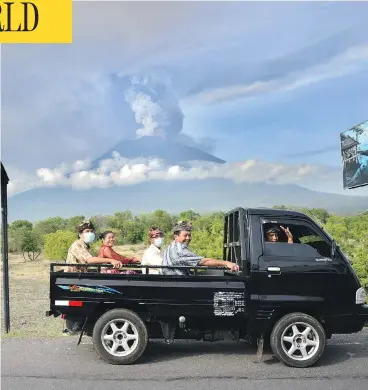  ?? SONNY TUMBELAKA/AFP/GETTY IMAGES ?? Residents ride past Mount Agung erupting on Indonesia’s resort island of Bali Monday. Flights to and from the island have been cancelled, and officials are warning a larger eruption is possible in the coming days.