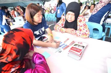  ??  ?? A Prudential volunteer explaining to PPR Taman Dahlia residents that PRUkasih is a free protection plan that provides financial aid in the event of a death, accident or illness.
