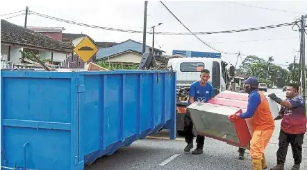  ?? ?? Out it goes: Workers collecting discarded furniture that were damaged by the floods during a clean-up operation in Johor Baru.