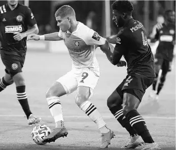  ?? STEPHEN M. DOWELL/ORLANDO SENTINEL ?? Philadelph­ia Union's Mark McKenzie (4) grabs the arm of OC's Chris Mueller (9) in a match on Monday in Orlando.