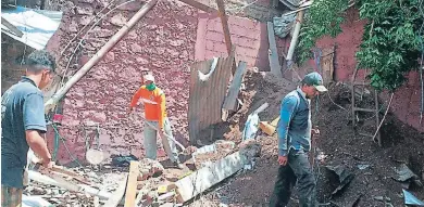  ?? FOTO: EL HERALDO ?? Miembros de Copeco limpian los escombros de una pared que cedió por las fuertes lluvias en La Trinidad.