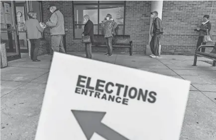  ?? DAVID GOLDMAN/AP ?? Voters line up in Sterling Heights, Mich. President Donald Trump took the state in 2016, but Joe Biden took a 2.69% lead over Trump in the state this election.