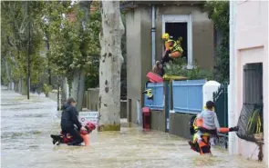  ??  ?? Firefighte­rs help youngsters evacuate during a rescue operation following heavy rains that saw rivers bursting banks in Trebes, near Carcassone, southern France.