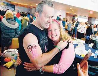  ??  ?? Dennis Turner hugs his wife and breast cancer survivor Debbie Turner of Ringwood in East Rutherford, New Jersey, on Sunday, October 9. Turner sports an airbrushed tattoo from the ‘Celebratio­n Life and Liberty’ event hosted by the John Theurer Cancer...