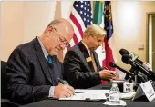  ?? ALYSSA POINTER / ALYSSA. POINTER@ AJC.COM ?? Francisco Javier Diaz De Leon (left) and Tom Rawlings sign a deal to help immigrant kids in Georgia.