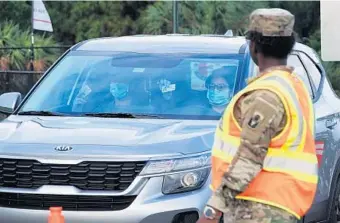  ?? JOE CAVARETTA/SOUTH FLORIDA SUN SENTINEL ?? National Guard troops direct people lined up in cars waiting for COVID-19 testing Monday at the FiTTeam Ballpark.
