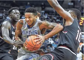  ?? MARK WEBER/THE COMMERCIAL APPEAL ?? University of Memphis forward K.J. Lawson (middle) puts up a shot against the University of South Carolina defense during a game at FedExForum.