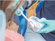  ?? FOTO: CHRISTIN KLOSE/DPA ?? In der Zahnarztpr­axis wird es erklärt: Mit einer oszilliere­nd-rotierende­n Elektrozah­nbürste muss jeder Zahn einzeln für jeweils einige Sekunden geputzt werden.