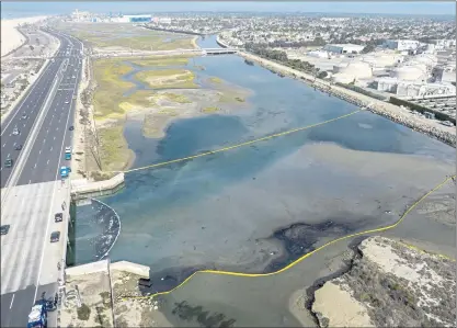  ?? JEFF GRITCHEN — SOUTHERN CALIFORNIA NEWS GROUP ?? Booms float in the Talbert Marsh as workers try to limit the spread of oil from a spill from an offshore platform in Huntington Beach on Monday. Officials say about 126,000 gallons of oil was leaked from a ruptured pipe, forcing the closure of several beaches in the area.