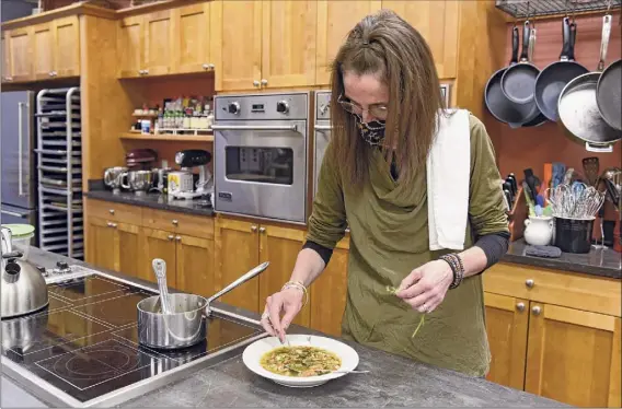  ?? Lori Van Buren / Times Union ?? Caroline Barrett garnishes her springtime minestrone with green garlic broth at Different Drummer's Kitchen in Albany.