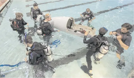  ??  ?? A group of UVic and Camosun College students take the human-powered submarine they built for an inaugural lap around McKinnon Pool. The submarine club is planning to attend its first competitio­n, in Gosport, England, from July 3 to 12.