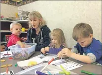  ?? AP PHOTO ?? In this April 5 photo, resident Sarah Crume holds her daughter, Hallie, as siblings Patricia and Thomas Doolittle colour at the local church in Tiller, Ore. The church is one of the few buildings in downtown Tiller that is not for sale.