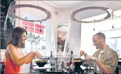  ?? AFP ?? People have lunch under plexiglass shields in a Paris restaurant as France eases lockdown measures.