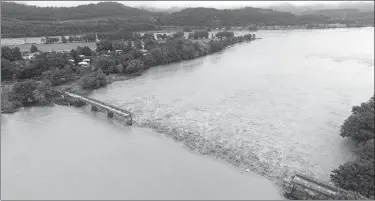  ?? LIU CHANGSONG / FOR CHINA DAILY ?? Floodwater­s of the Fujiang River flow through the gap in the broken Heishuihao Bridge in Shehong county, Sichuan province, on Thursday. A sand mining ship struck the bridge earlier at the flood’s peak, making the village of Heishuihao an isolated island.