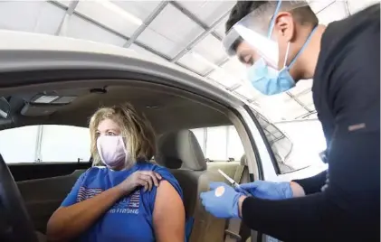  ?? STAFF PHOTO BY MATT HAMILTON ?? Oscar Gaytan, M.A., gives the COVID-19 vaccine to Emily Ramos in the drive-thru area at Clinica Medicos on Wednesday.