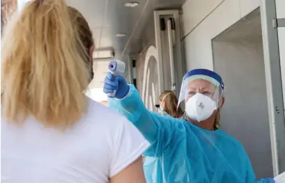  ?? GEtty IMagEs ?? VIRUS STILL ACTIVE: A health worker takes a patient’s temperatur­e before sending them to a tent to be tested at a COVID-19 testing site at St. John’s Well Child and Family Center, in Los Angeles, Calif., on July 24, as U.S. cases just topped the 5 million mark.