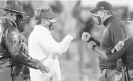  ?? BRYNN ANDERSON/AP ?? Georgia coach Kirby Smart, left, and Auburn coach Gus Malzahn, right, meet with masks on for a fist bump after their game on Oct. 3.