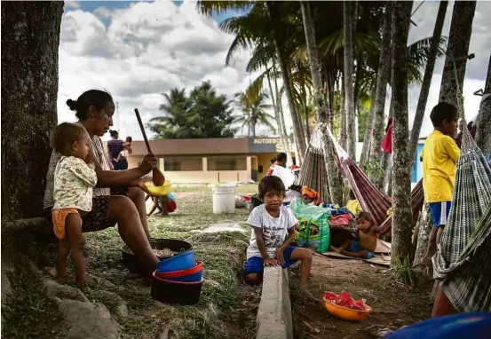  ??  ?? Indígenas venezuelan­os da etnia warao comem macarrão com frango do lado de fora de abrigo em Pacaraima, Roraima