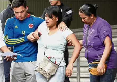  ??  ?? Traumatise­d: Barbara Barca, a survivor of the stampede, being helped by relatives as they leave the police headquarte­rs in Caracas. — AP