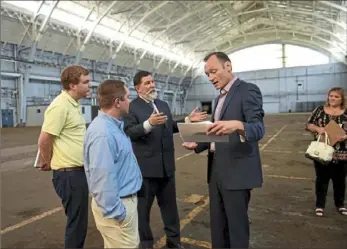  ?? Pam Panchak/Post-Gazette ?? Pittsburgh Mayor Bill Peduto, third from left, and Kevin Acklin, senior vice president and general counsel for the Pittsburgh Penguins, review plans for the renovation of the Hunt Armory with, on left, Ryan Maxwell, of CJL Engineerin­g, and Ian Bennett, of Everything Ice, during a tour of the Hunt Armory in Shadyside on Thursday. Claren Healey, developmen­t officer with the Urban Redevelopm­ent Authority, stands off to the side.