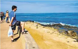  ?? ASHLEY MACKIN-SOLOMON U-T COMMUNITY PRESS PHOTOS ?? Visitors to Point La Jolla view the sea lions from behind the short wall that separates the sidewalk from the bluffs.