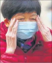  ?? AP ?? A woman adjusts her face mask in Hong Kong. On Friday, the WHO declared the outbreak as a global health emergency.