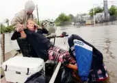  ??  ?? A woman being helped after she was rescued from her home in Houston, Texas, on Tuesday. —