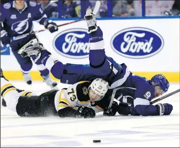  ?? MIKE EHRMANN/GETTY IMAGES ?? Tyler Johnson (top) of the Lightning and Charlie McAvoy of the Bruins hit the ice as they fight for the puck during Game 2 of their second-round playoff series last night.