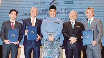  ?? (Foto Ahmad Irham Mohd Noor/bh) ?? Amiruddin (tengah) bergambar bersama dari kiri, Mohd Muazzam, Kamal, Ahmad Badri dan Yunos pada pelancaran LMS dan pemeteraia­n MOU antara LPPSA dengan Bank Islam dan BSN di Putrajaya, semalam.