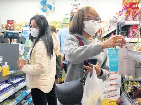  ?? AP ?? COVID-19 has people the world over anxious. Here, people wear protective face masks as they make purchases from a convenienc­e store in Hong Kong.