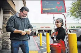  ?? Caroline Brehman Las Vegas Review-Journal ?? Esther Mowtelro accepts a gift Wednesday for the Salvation Army from Tom Engel.