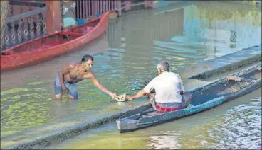  ?? BLOOMBERG ?? A man standing in floodwater shares tea with another man sitting in a canoe in Kerala’s Alappuzha district.