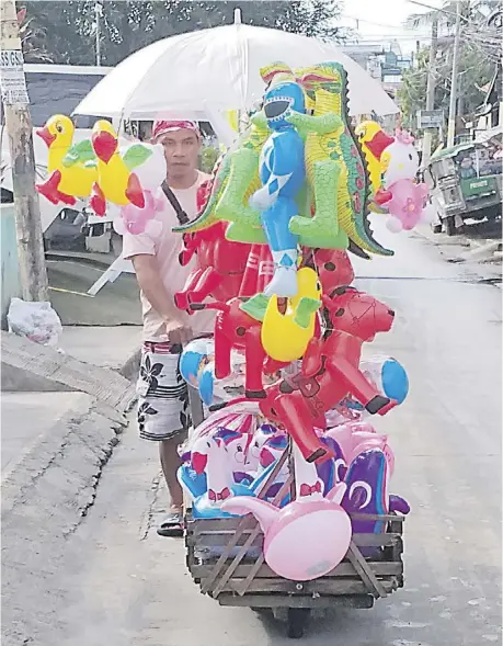  ?? PHOTOGRAPH BY JON GAMBOA FOR THE DAILY TRIBUNE ?? Sale window With the Yuletide season on its last leg, a vendor tries to sell as many balloons in Caloocan City Friday, 30 December 2022 — highly mobile with his wooden cart.