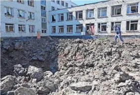  ?? SERGEY BOBOK/AFP VIA GETTY IMAGES ?? A Ukrainian de-miner examines a crater caused by missiles that hit a schoolyard in a residentia­l area of Kharkiv on Monday.