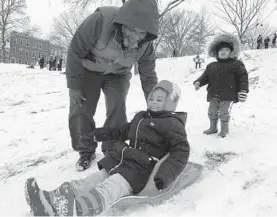 ?? COLIN CAMPBELL/BALTIMORE SUN ?? Aberina Kelly, 5, of Federal Hill is ready to go in her pink-and-rainbow winter hat, assisted by a push at the top from her father, Tim Kelly, while her brother Taylen Allen, 2, watches.