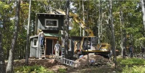  ?? KATE ANDRIES/MCT ?? A piece of roof is guided into place during an installati­on of a hob at the Blue Moon Rising resort in McHenry, Md. Hob homes sleep up to four people.