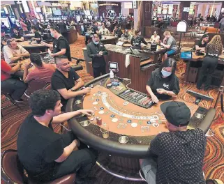  ?? ETHAN MILLER
GETTY IMAGES ?? After guests had their temperatur­es checked at the door, the casinos were quickly crowded with revelers and gamblers, while the dealers wore face masks or shields.