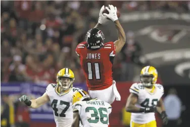  ?? Streeter Lecka / Getty Images ?? Atlanta’s Julio Jones, who had been bothered by a foot injury, soars over Green Bay’s LaDarius Gunter to haul in a third-quarter pass. Jones finished with nine catches for 180 yards and two touchdowns.