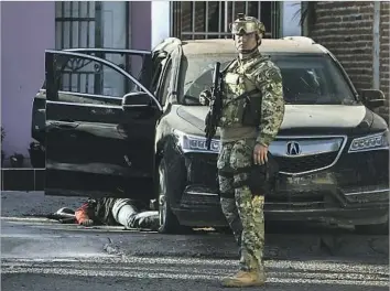  ?? Rashide Frias Associated Press ?? A MEXICAN MARINE stands near the body of a gunman last month in Culiacan, Sinaloa state. Authoritie­s said heavily armed men attacked the patrolling troops, starting a gunfight that left one marine dead.