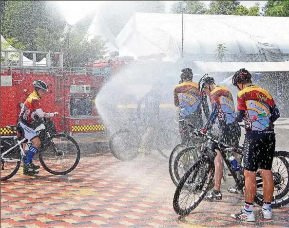  ??  ?? Cyclists enjoying a shower from a fire engine after a marathon ride in penang. Less dramatic bath facilities are needed to promote cycling in malaysia. — Filepic