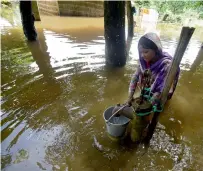  ?? AFP ?? A girl fetches drinking water from a submerged hand pump in a flood-hit village in Morigaon district of Assam, India. —