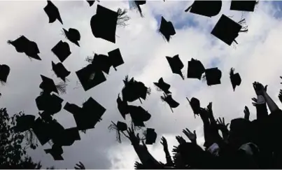  ??  ?? UNCERTAINT­Y: Students throw their mortarboar­ds in the air on graduation day