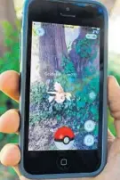  ?? GLENN CHAPMAN/GETTY IMAGES ?? A Pokemon called a Goldeen appears against the existing landscape on the phone of a Pokemon Go player.