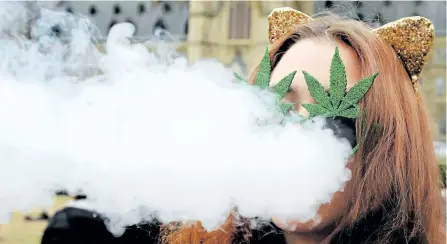  ??  ?? A woman smokes marijuana on Parliament Hill on April 20. A new Health Canada survey shows that Canadians are hazy on the risks of driving high.
