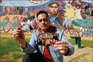  ?? ASSOCIATED PRESS ?? IN THIS FEB. 1, 2018 PHOTO, FILIPINO AMERICAN JEFF DEGUIA, 28, holds up family pictures at Unidad (Unity) Park in Los Angeles. DeGuia, 28, says it took his mother more than a decade to bring two sisters from the Philippine­s. “It’s definitely this idea...