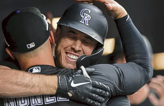  ?? Dustin Bradford, Getty Images ?? C.J. Cron of the Rockies is congratula­ted in the dugout by Dom Nunez after hitting a first-inning grand slam against the Milwaukee Brewers at Coors Field on Thursday night.